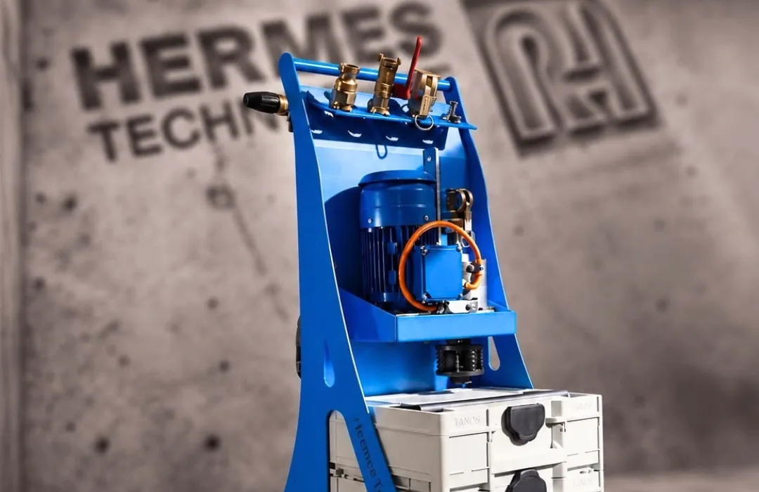 Hermes Trolley mit Schleudermotor, Kupplungen und Werkzeugkoffern vor einer Betonwand mit Hermes-Technologie-Logo