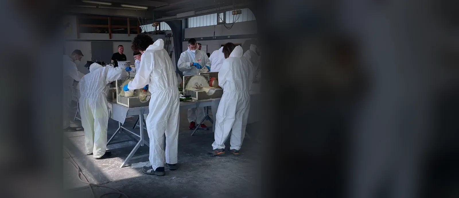 Kursteilnehmer in Schutzanzügen in der Schulungshalle